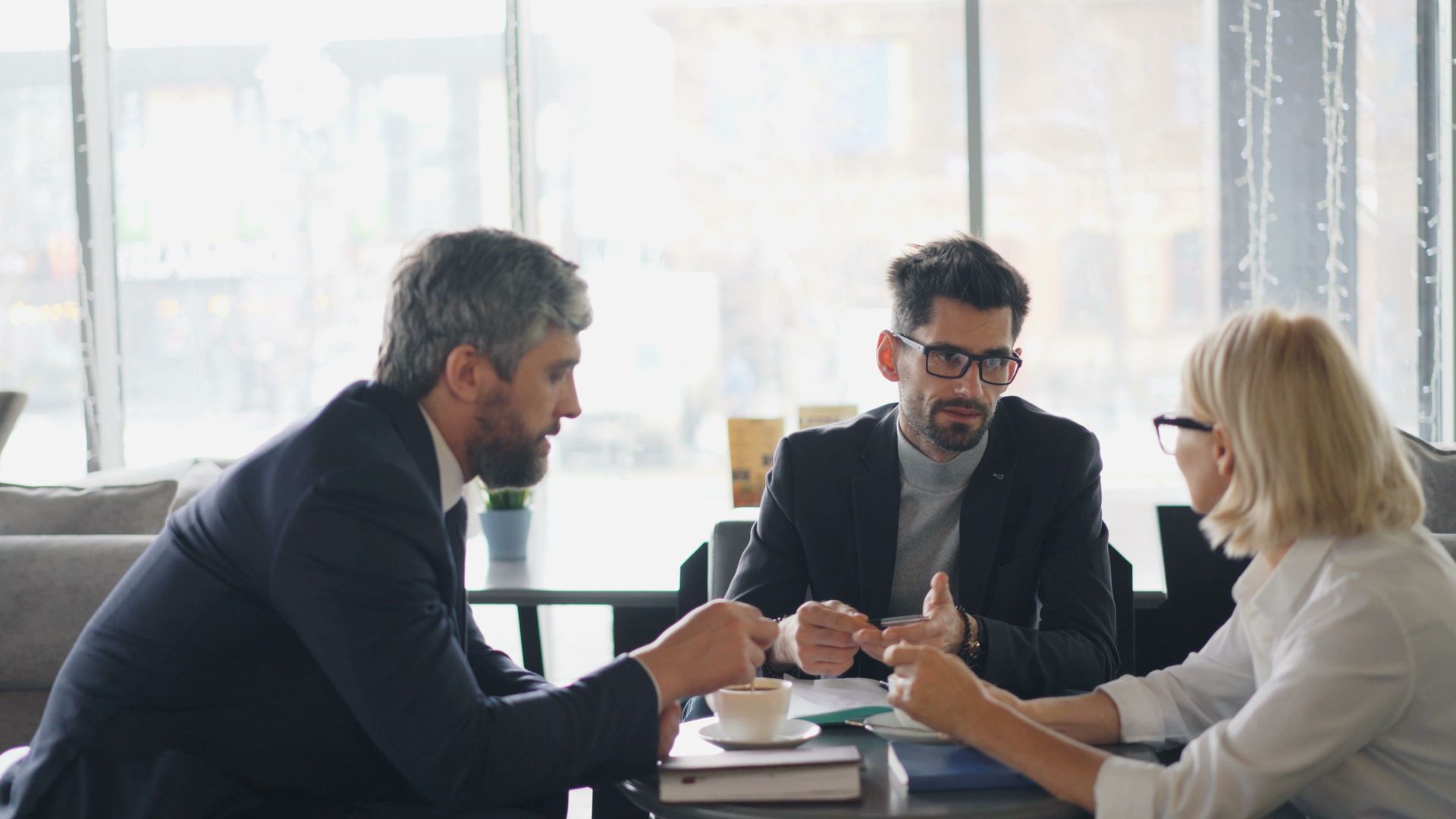 Three coworkers in a bright office discussing documents around a table