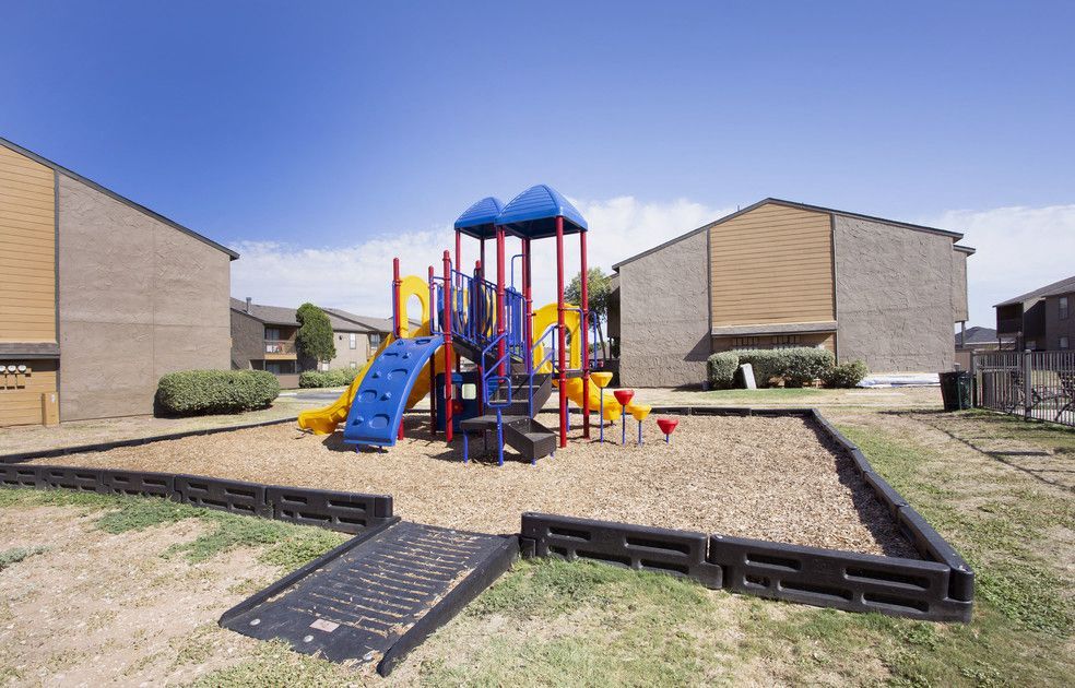 Outdoor playground with blue and red play structure in a residential apartment community.