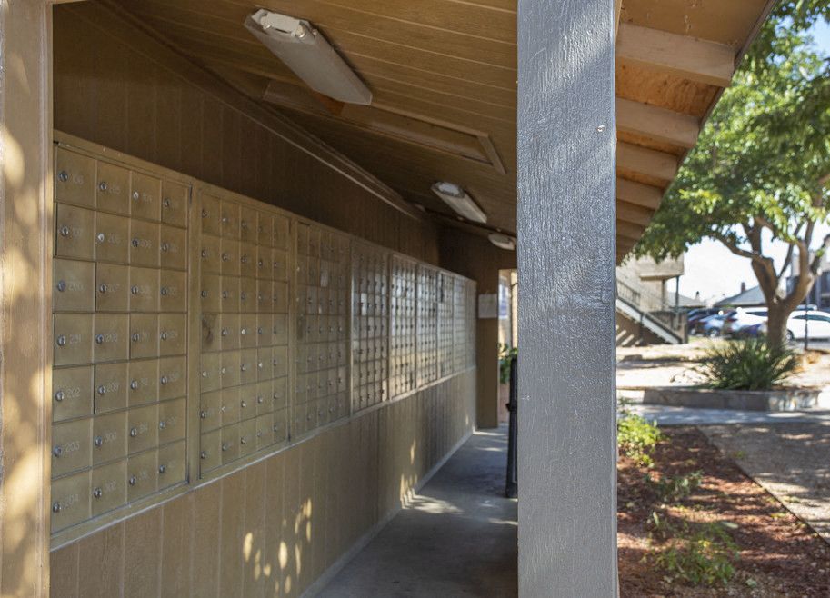 Row of apartment mailboxes lining a covered exterior walkway.