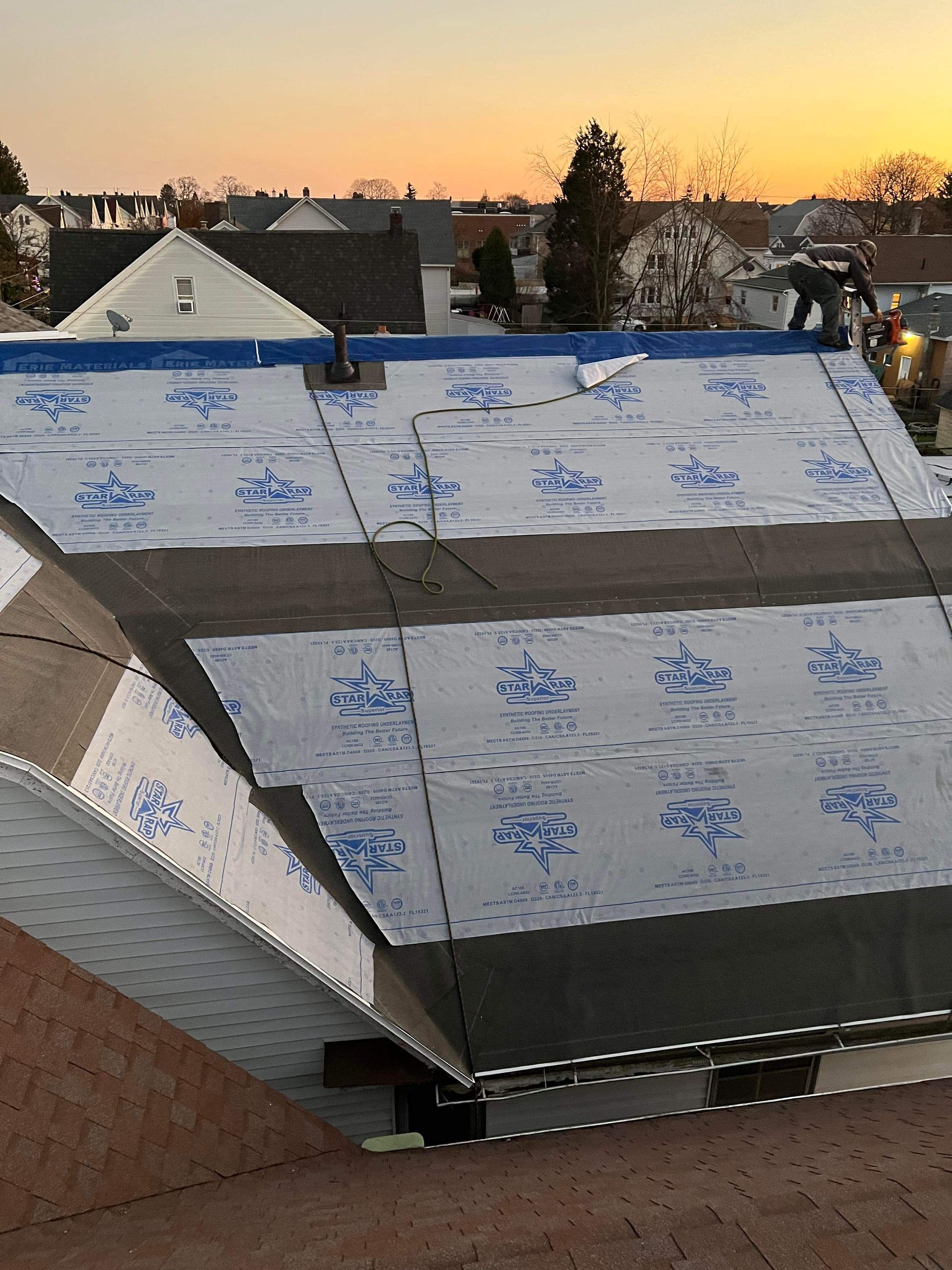 A roof with a lot of shingles on it and a sunset in the background