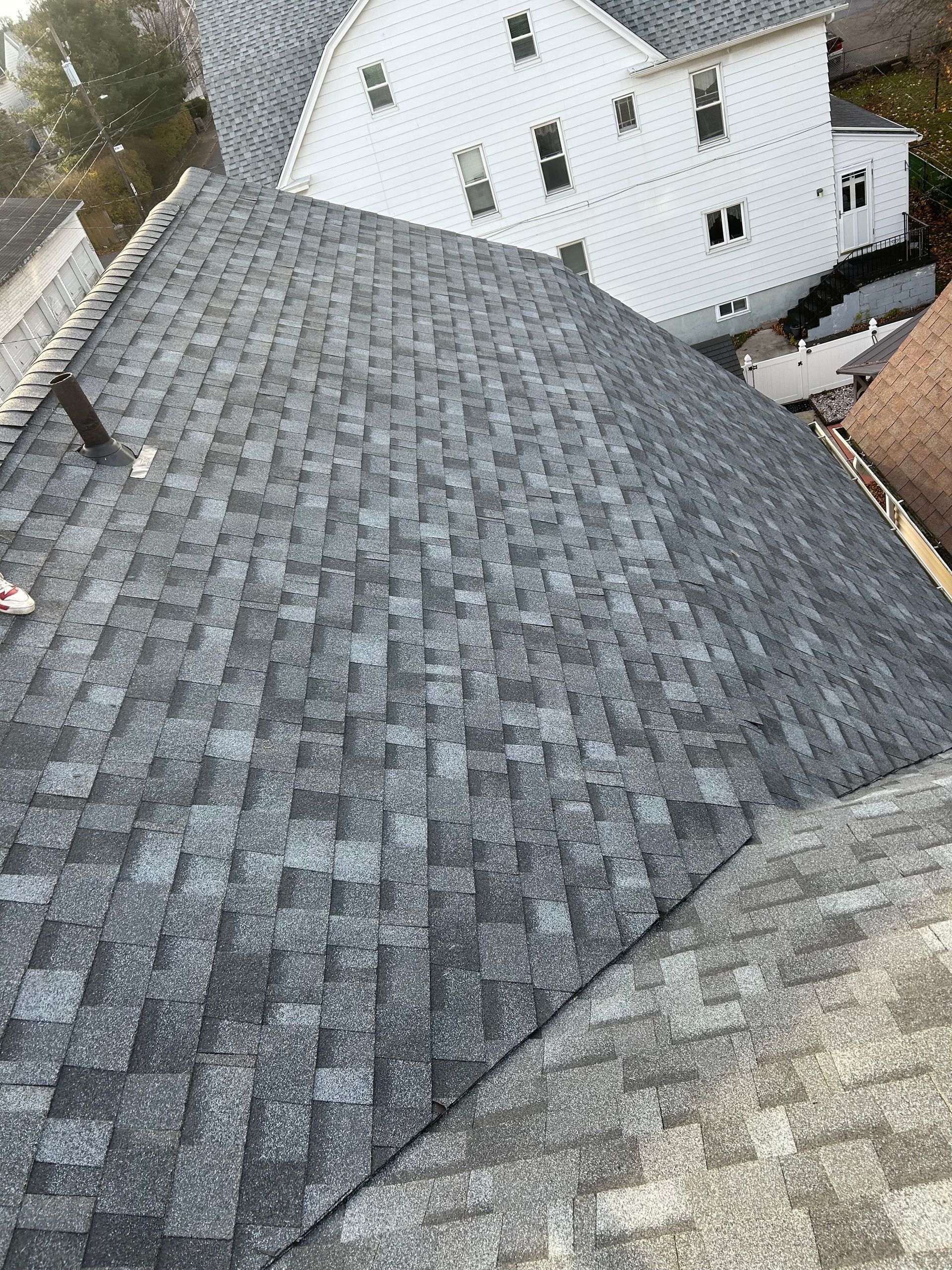 An aerial view of a roof with a white house in the background