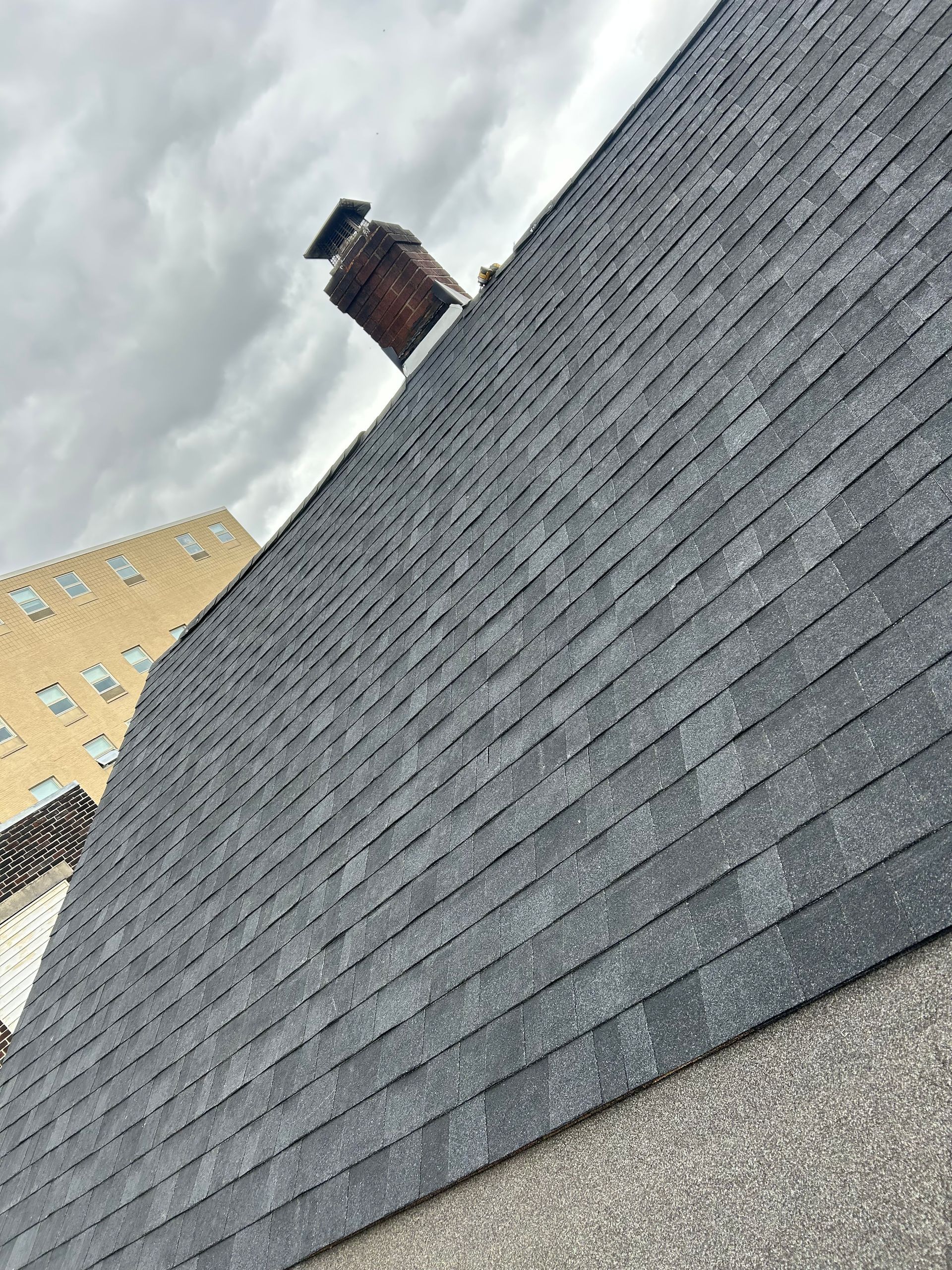 A roof with a chimney on top of it and a building in the background