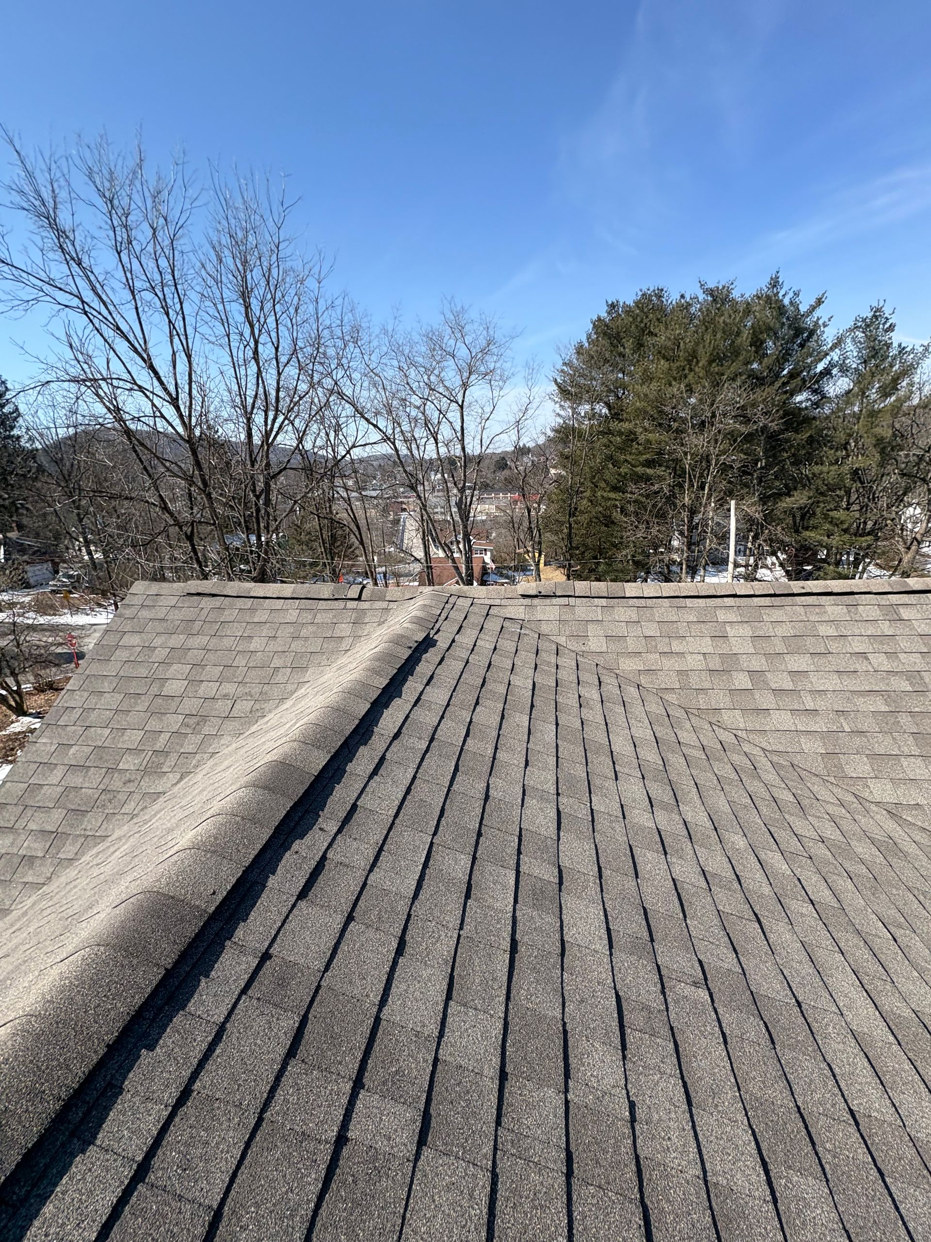 A roof with a lot of shingles on it and trees in the background