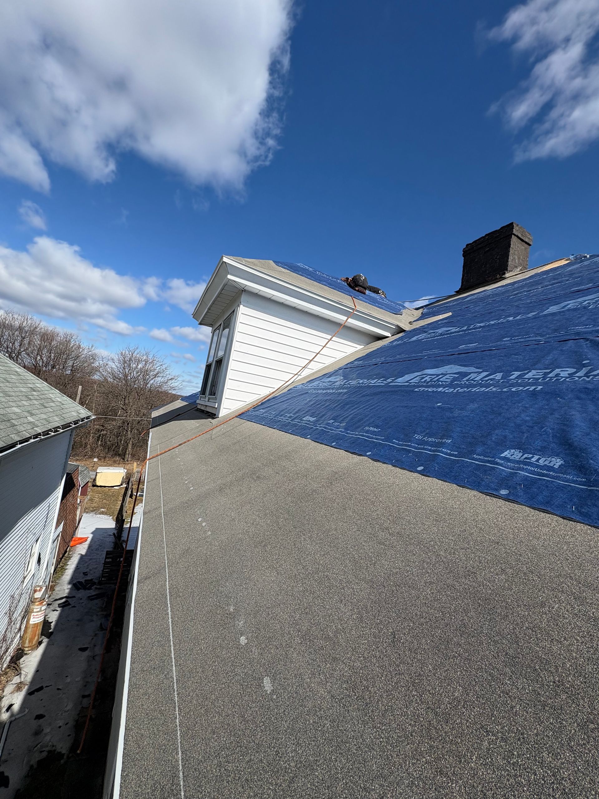 A roof of a house with a blue tarp on it