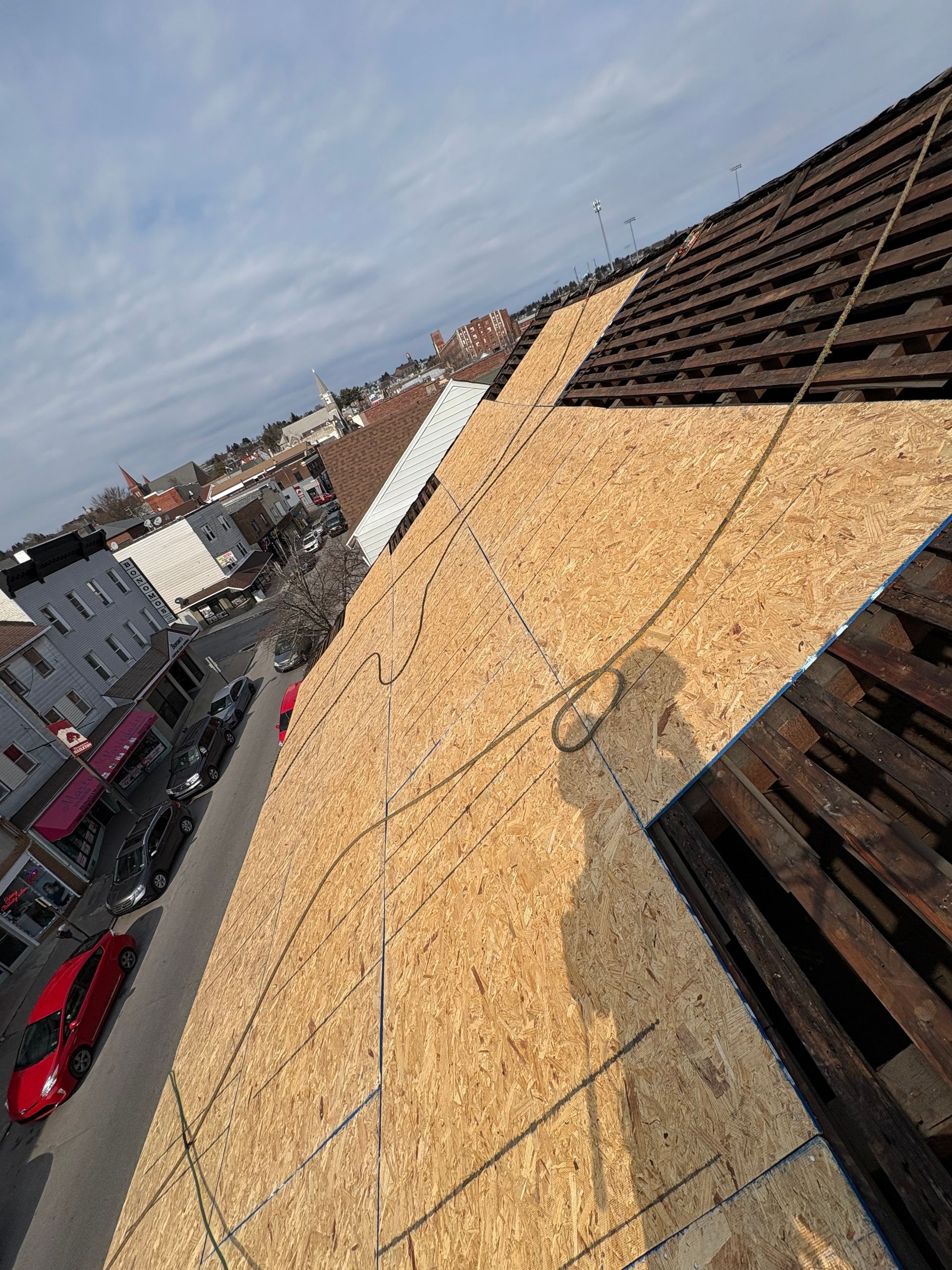 An aerial view of a roof with shingles being installed