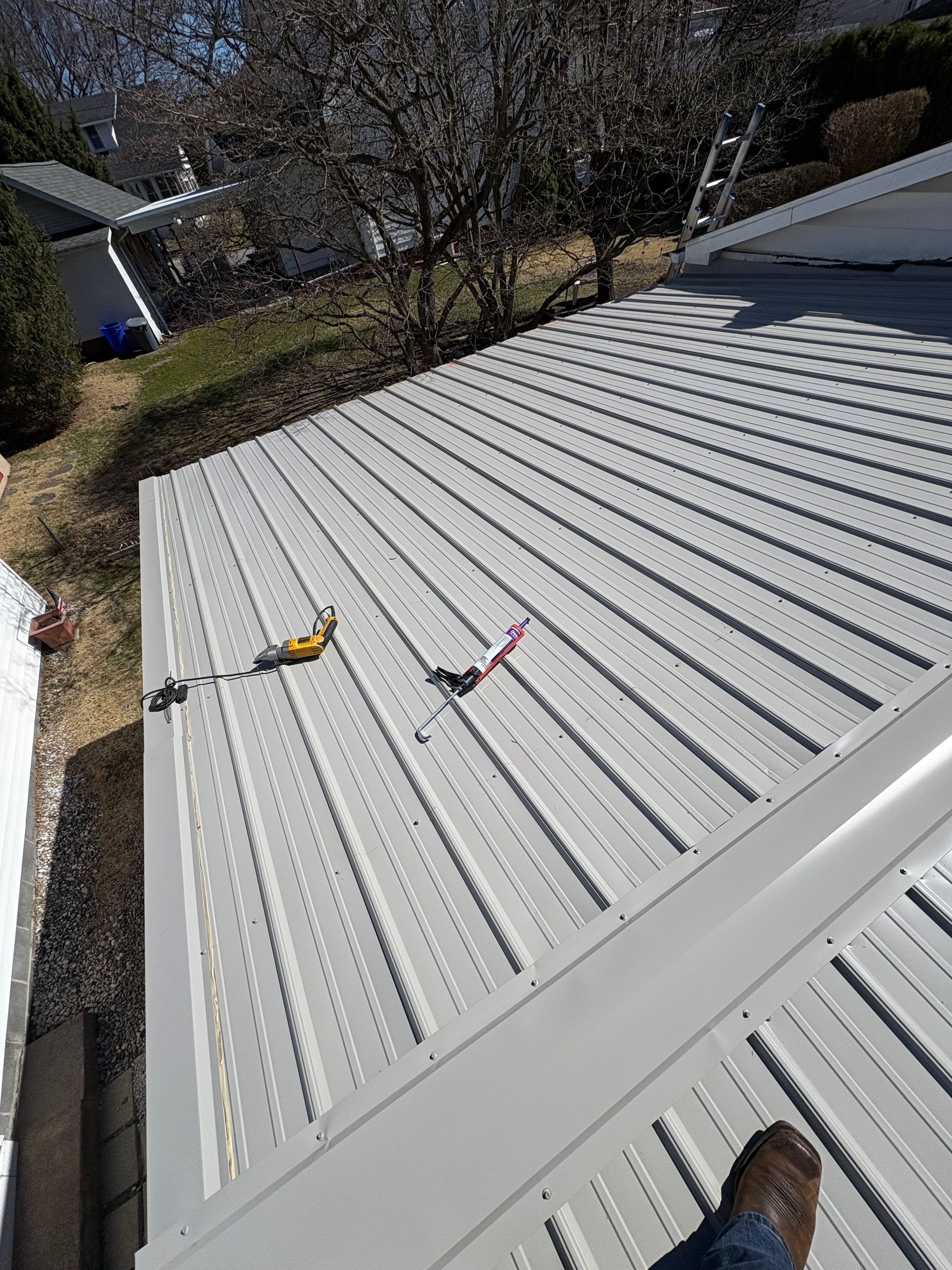A person is standing on top of a white metal roof