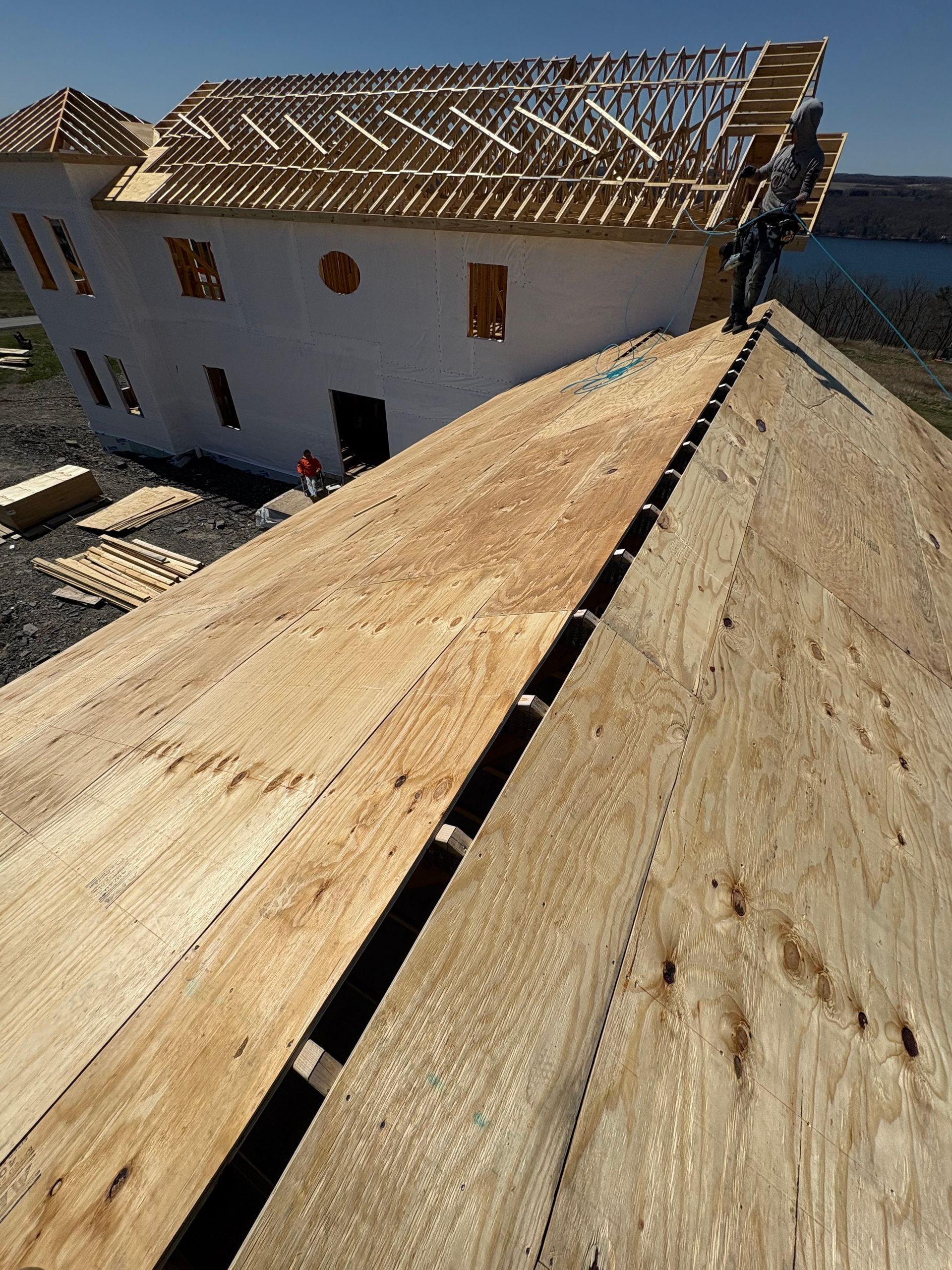 A man is standing on the roof of a house under construction