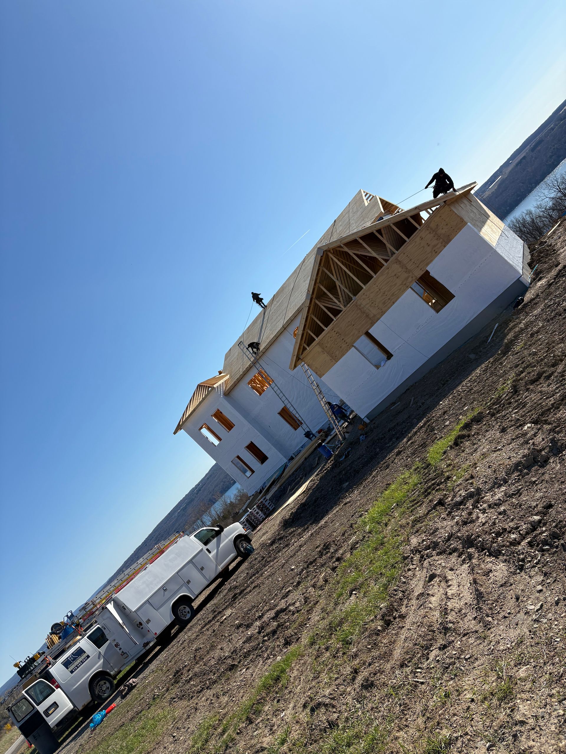 A house is being built in a field next to a body of water