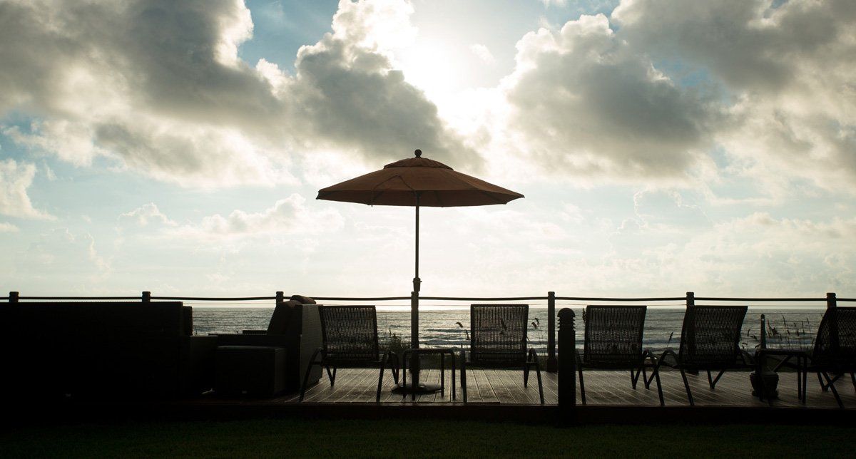 Un patio con sillas y sombrilla con vista al mar.
