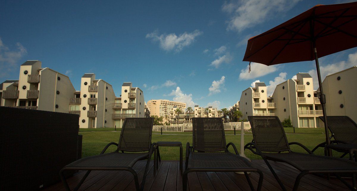 Una terraza con sillas y una sombrilla con edificios al fondo.