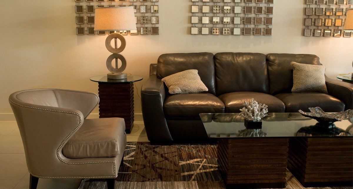 Una sala de estar con un sofá de cuero marrón y una mesa de centro de cristal.