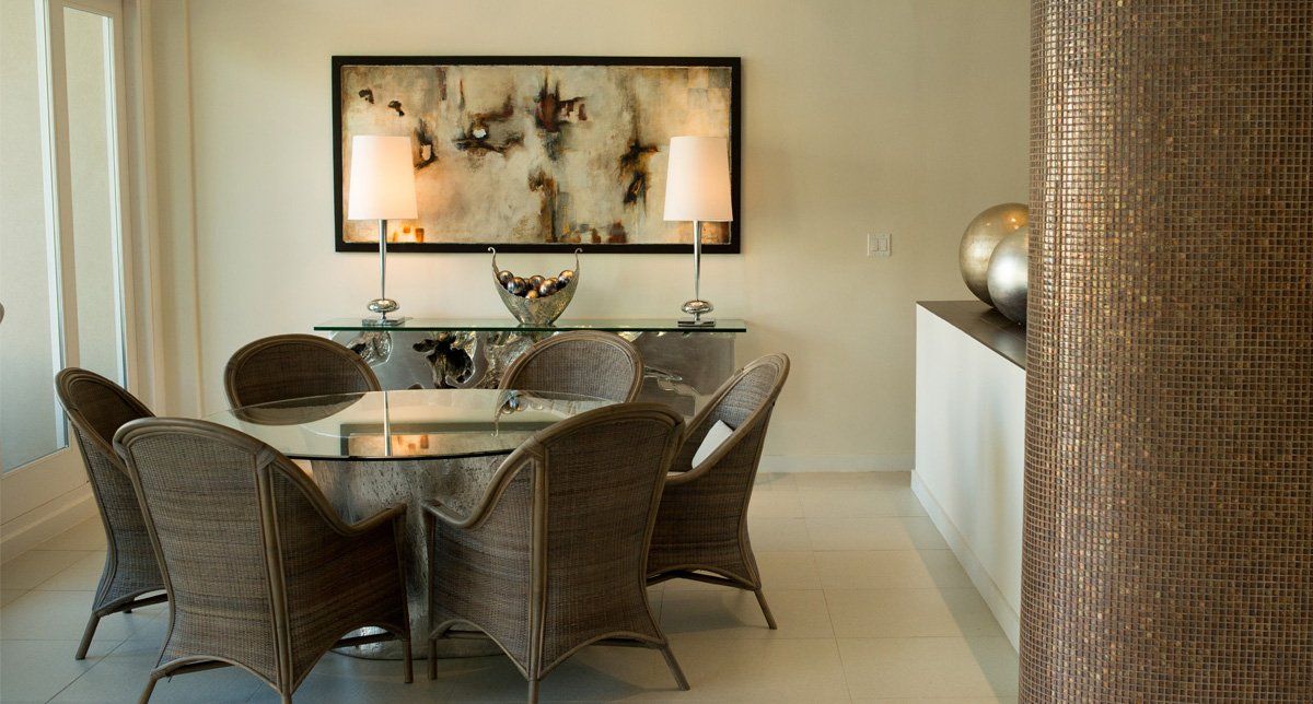 Un comedor con sillas de mimbre y una mesa de cristal.