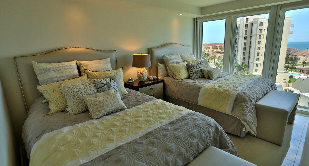 Un dormitorio con dos camas, un banco y una gran ventana.