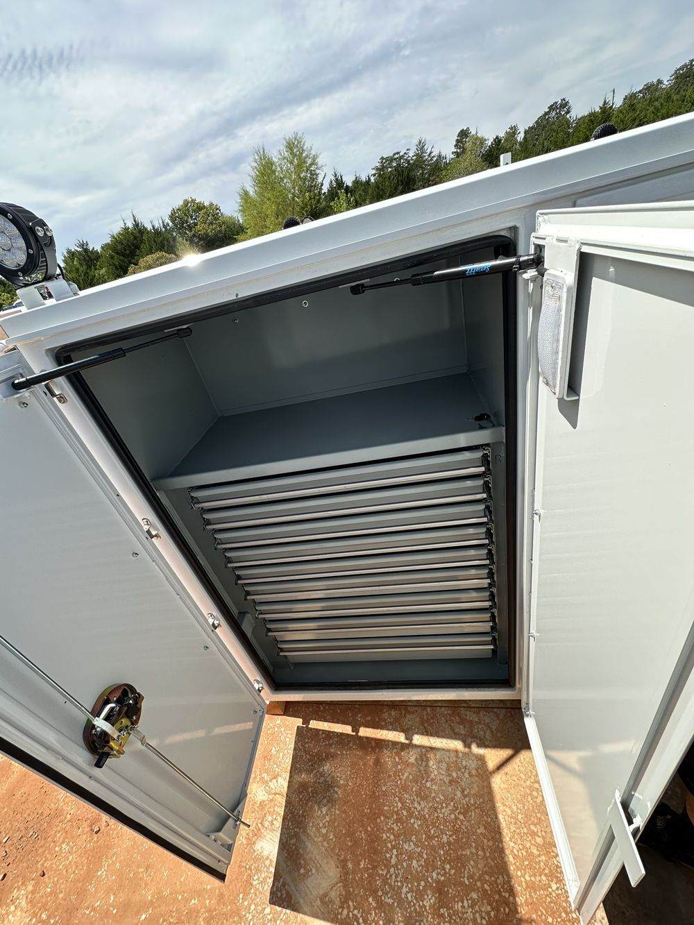A white cabinet with the doors open and a shelf inside of it.