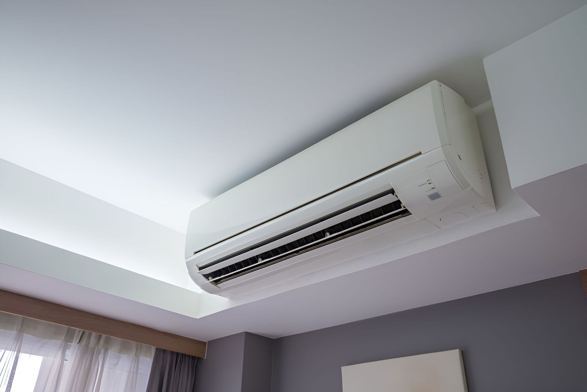 A White Air Conditioner is Hanging From the Ceiling in a Bedroom — Our Sparky In Urraween, QLD