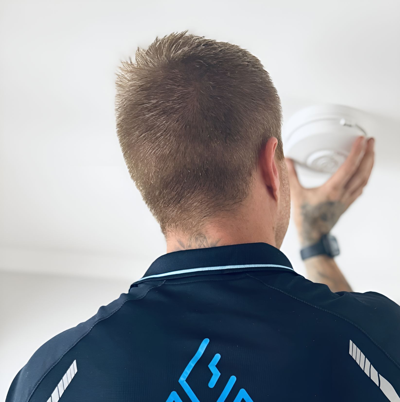 A man is holding a smoke detector in his hand — Our Sparky In Urraween, QLD