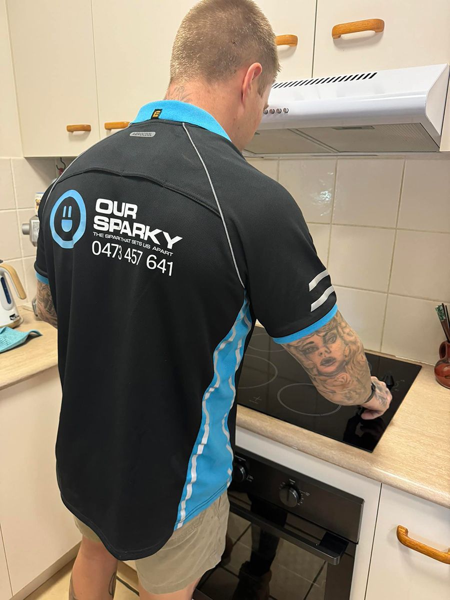 Electrician in Black and Blue Shirt, Working on a Cooktop in a Kitchen — Our Sparky In Urraween, QLD