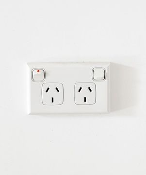 A white electrical outlet with two outlets and a switch on a white wall. — Our Sparky In Urraween, QLD