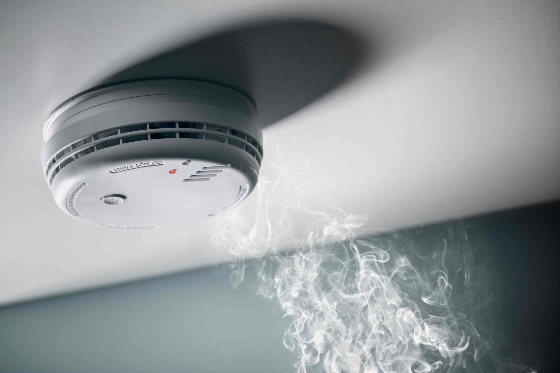 A smoke detector on the ceiling with smoke coming out of it. — Our Sparky In Urraween, QLD