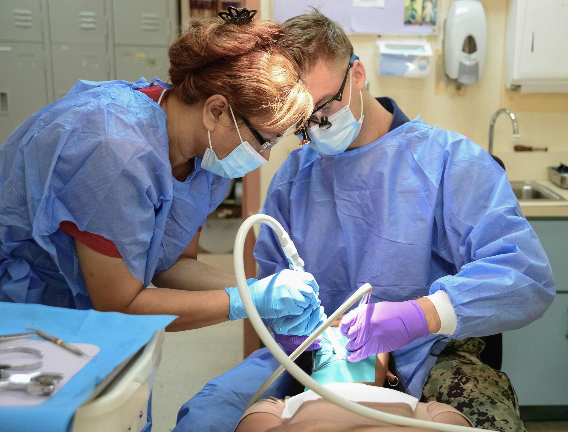 Two medical professionals performing dental work in a clinic.