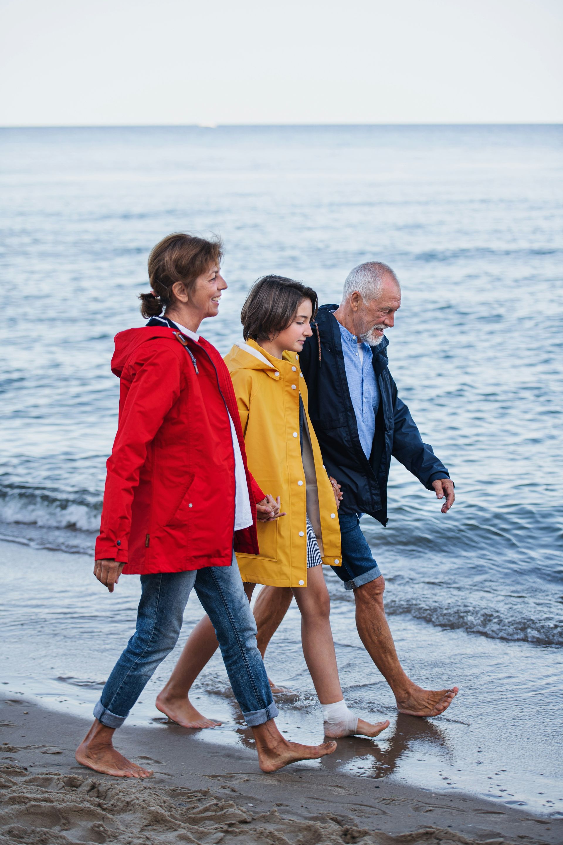 A family is walking along the beach barefoot.