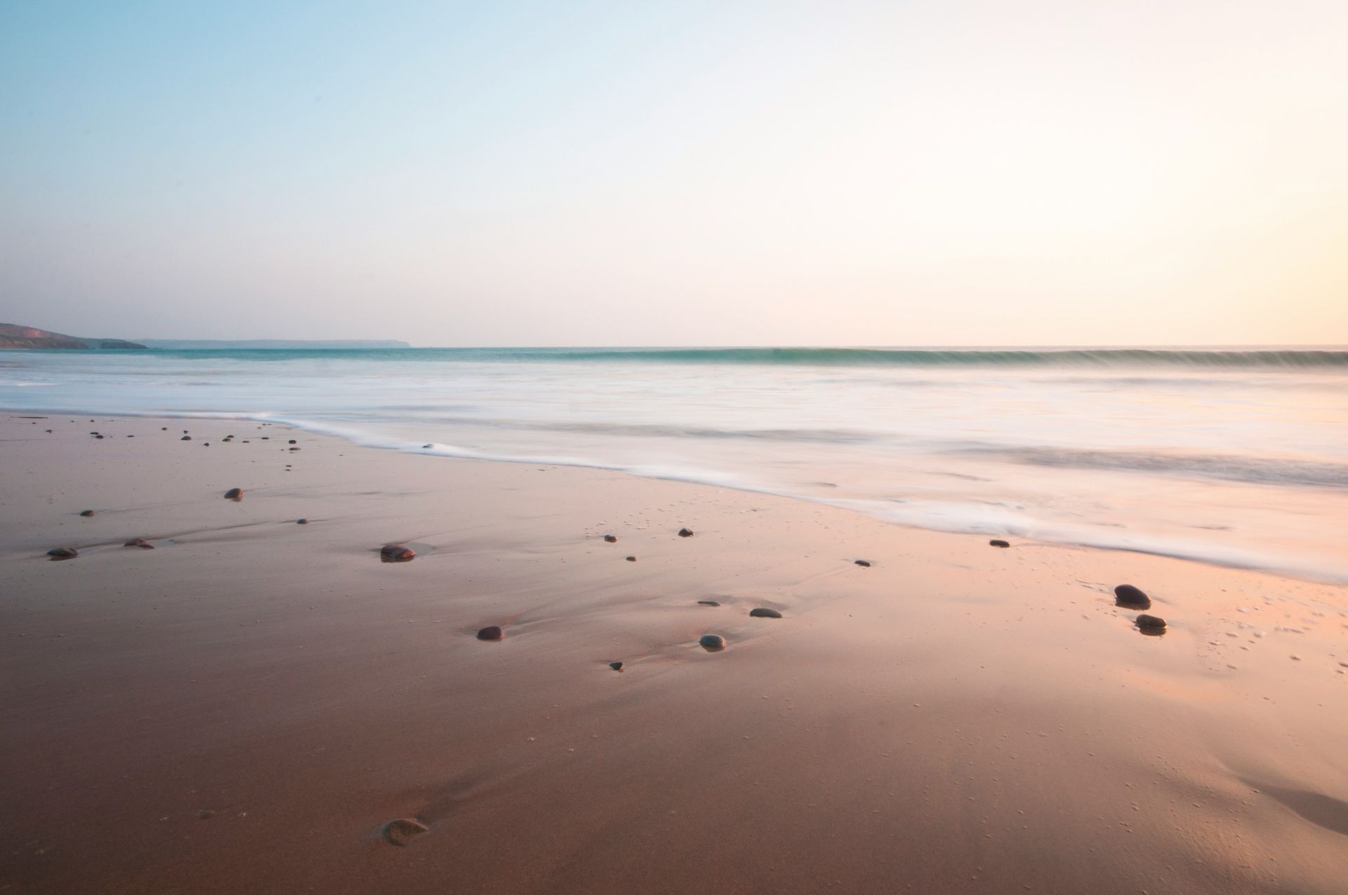 A blurry picture of a beach at sunset with waves coming in.