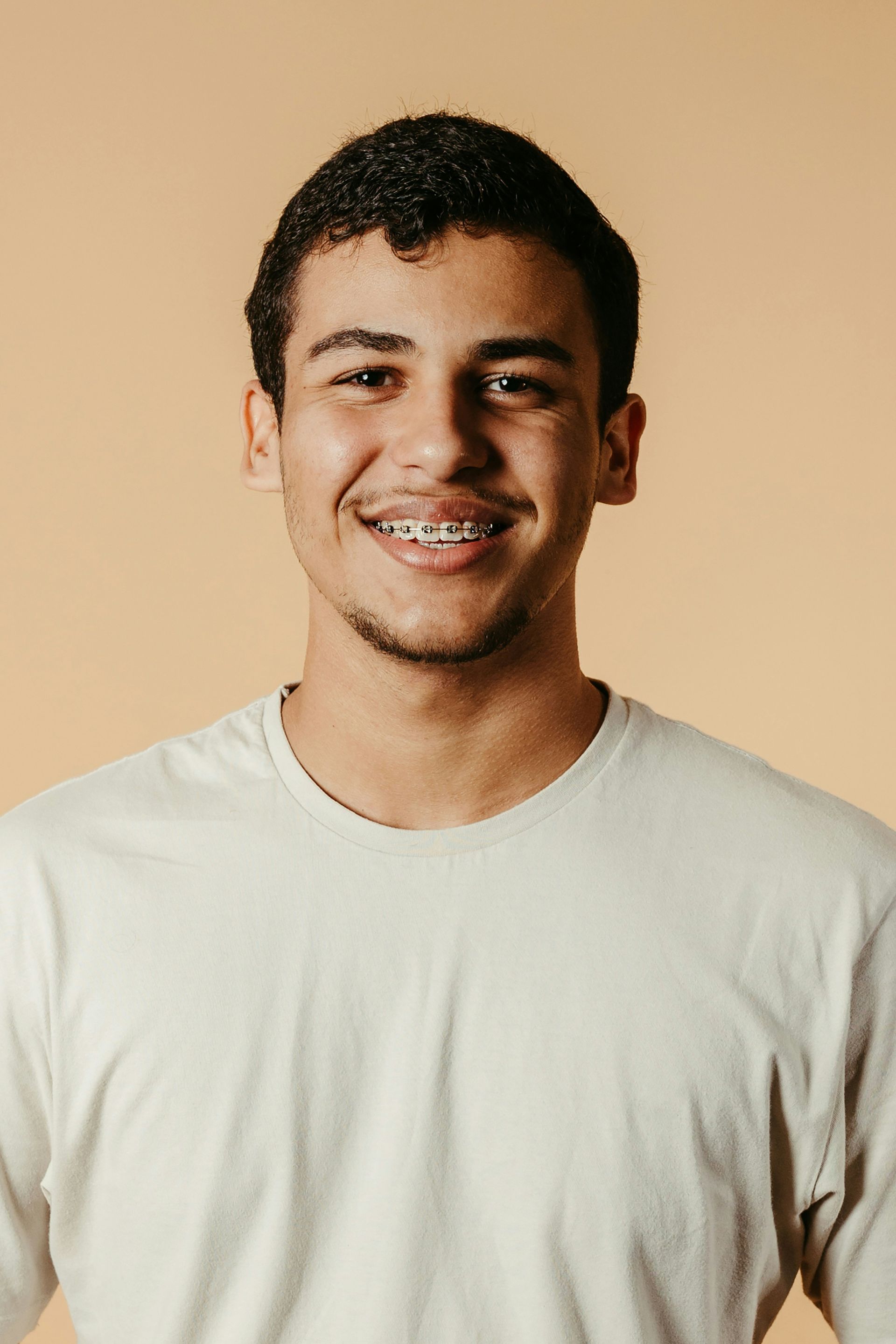 A young man with braces on his teeth is smiling for the camera.