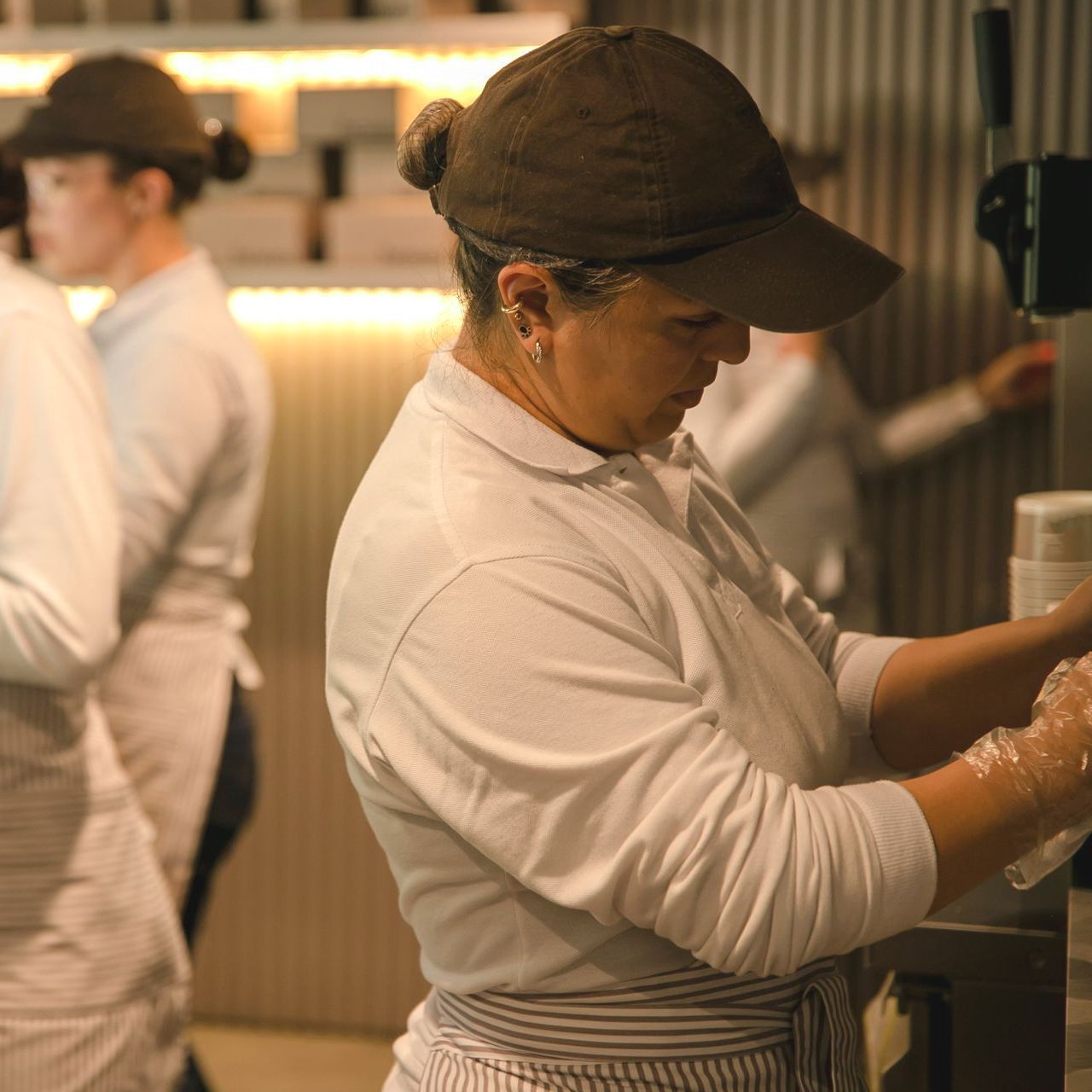 A woman wearing a brown hat is washing her hands