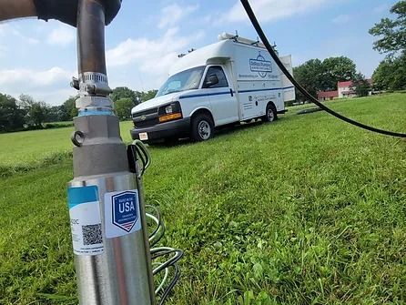 A white van is parked on the side of a grassy hill.