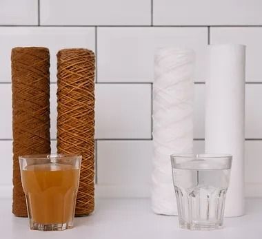 A glass of water is sitting next to a row of water filters.