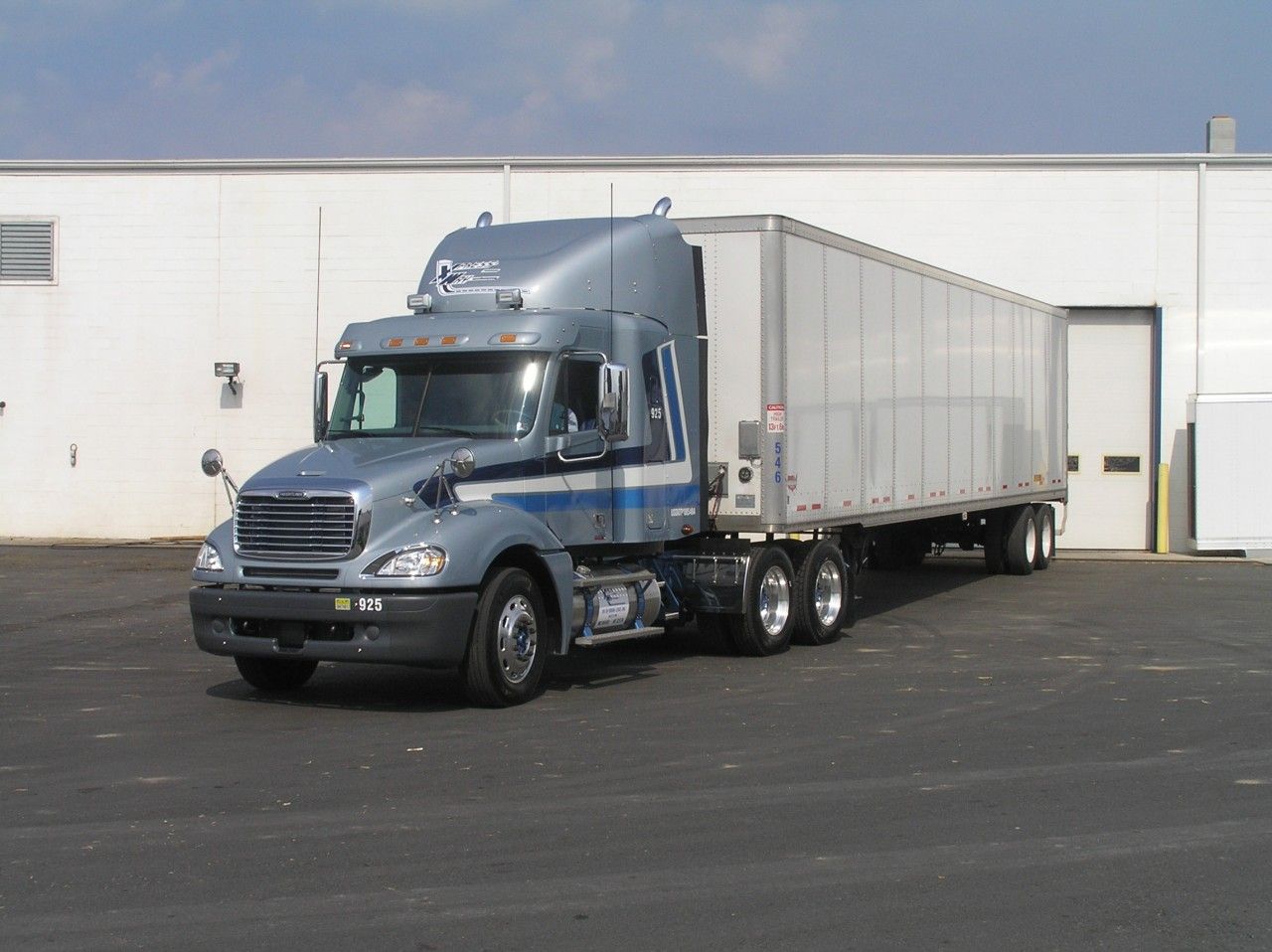 A semi truck is parked in front of a white building