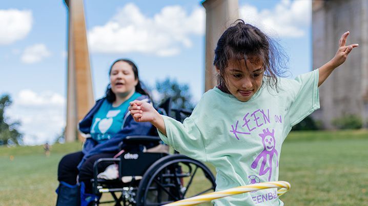 KEEN Athlete with hula hoop and woman in wheelchair in background