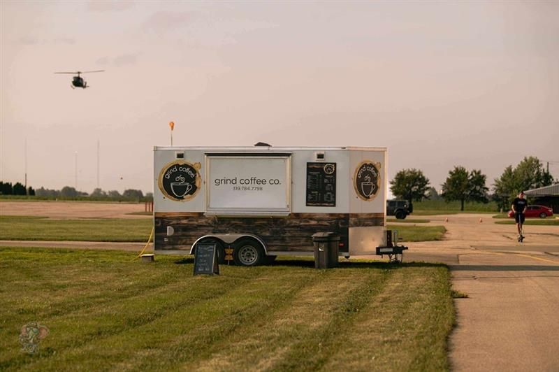 Coffee trailer on grass, a helicopter in the sky, and a person running.