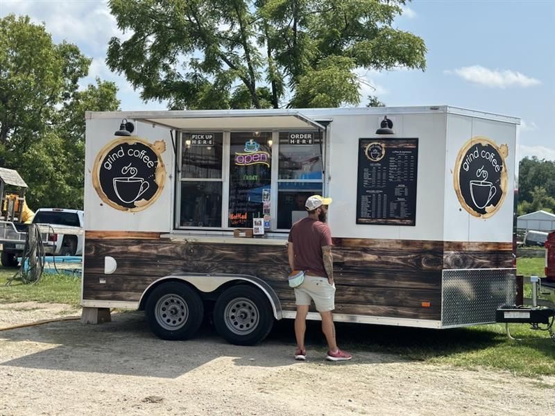 Coffee trailer with a menu board, and a customer is looking at the menu.