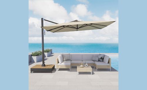 Beige cantilever umbrella shading a sectional sofa by a pool with ocean view