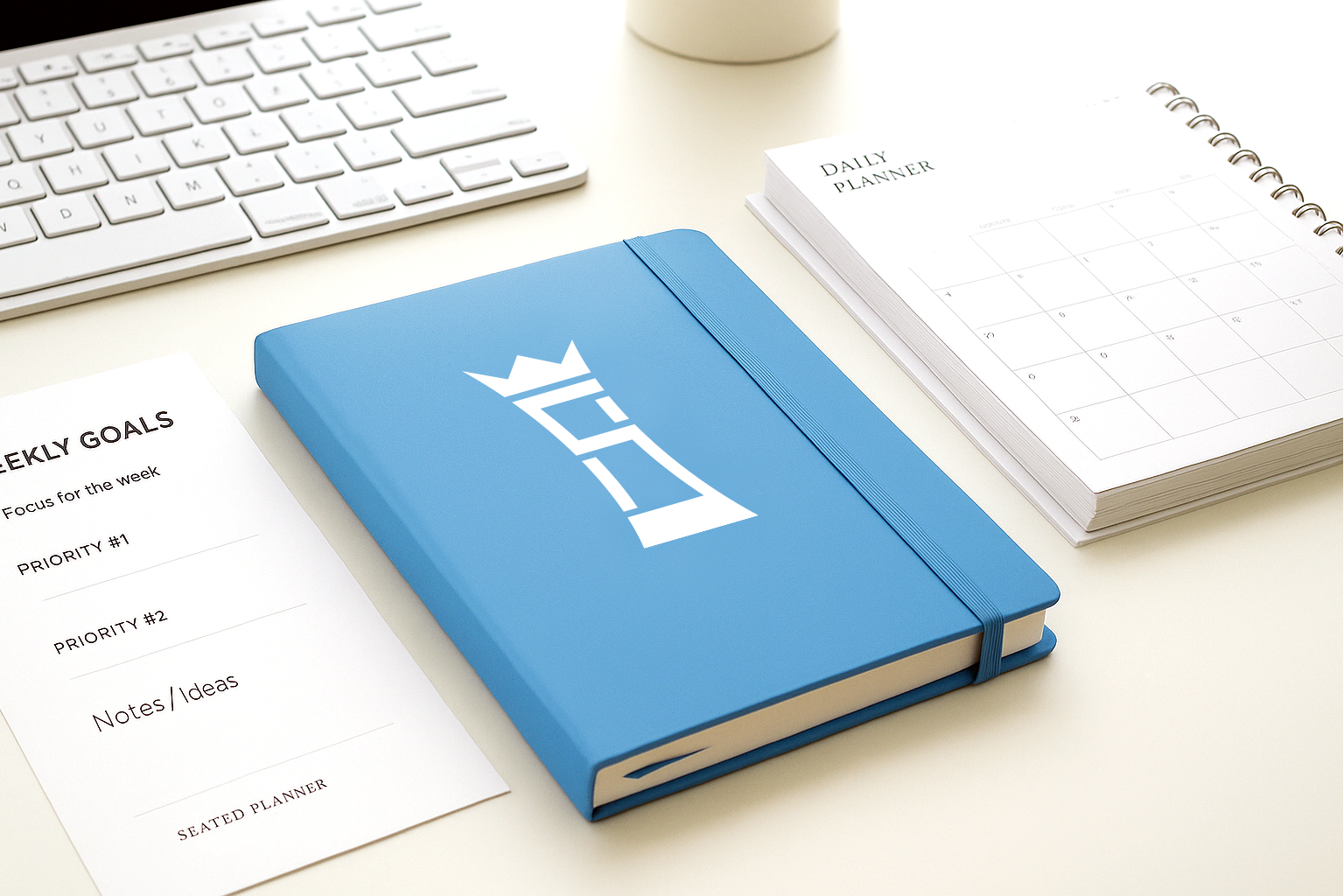 A blue notebook is sitting on a desk next to a keyboard.