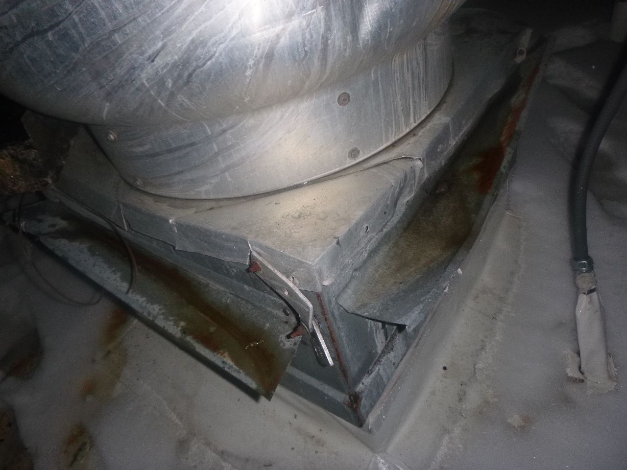 A metal duct is sitting on top of a concrete floor.
