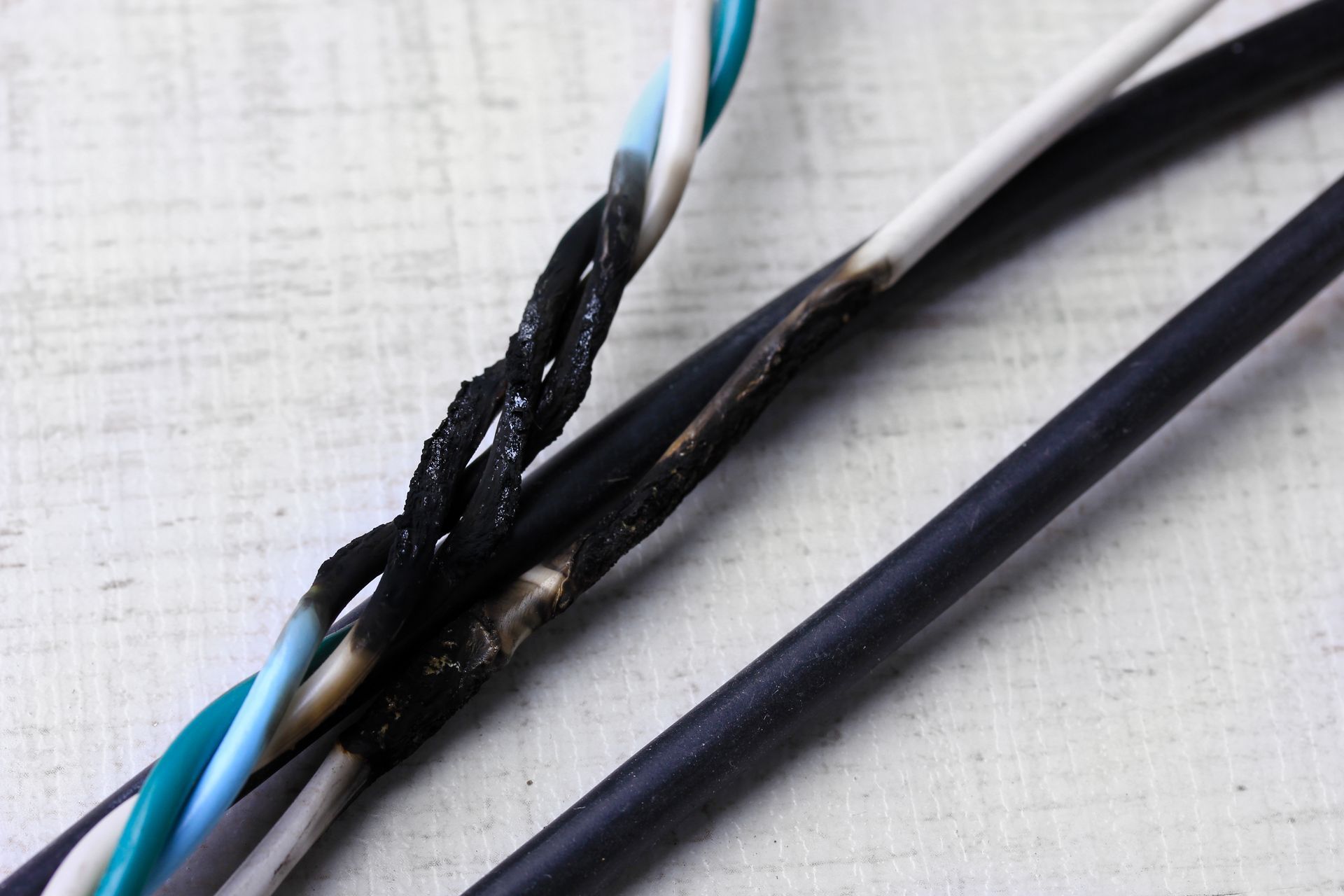 Damaged electrical wires, with burnt and melted insulation exposing the inner wires.