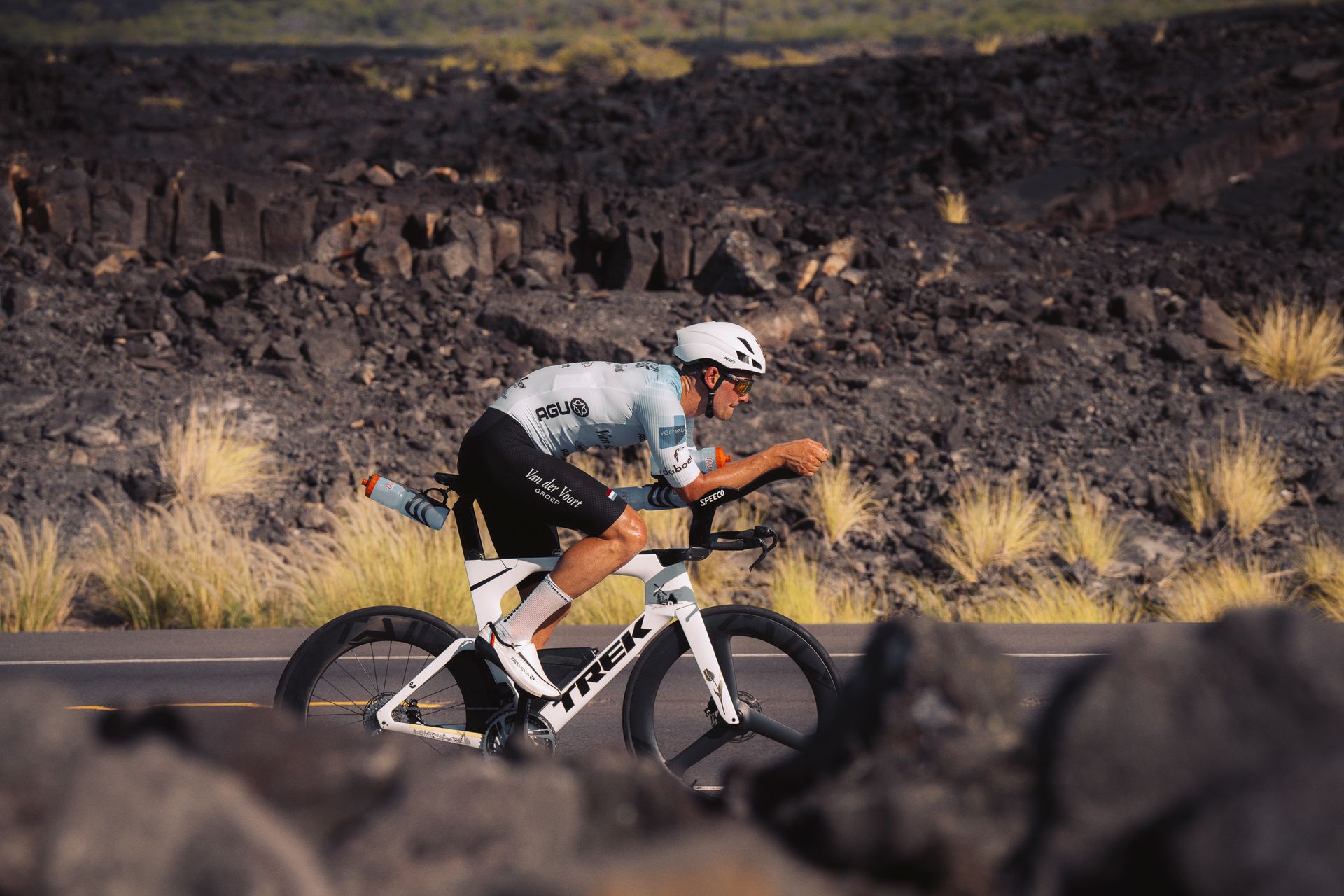 A man is riding a TT bike on a road in Kona, with triathlon carbon Tailwind wheels.