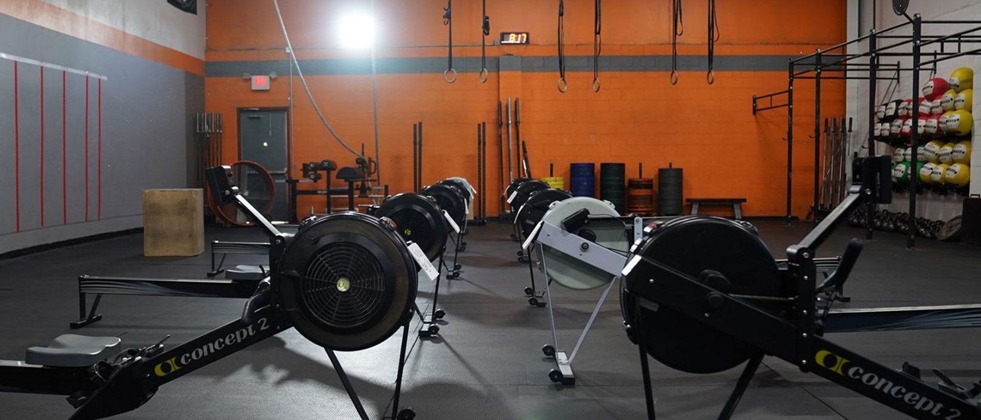 A group of rowing machines are sitting in a gym.