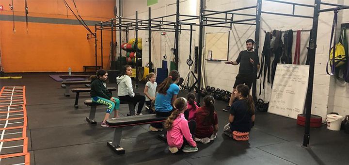 A group of children are sitting on benches in a gym.