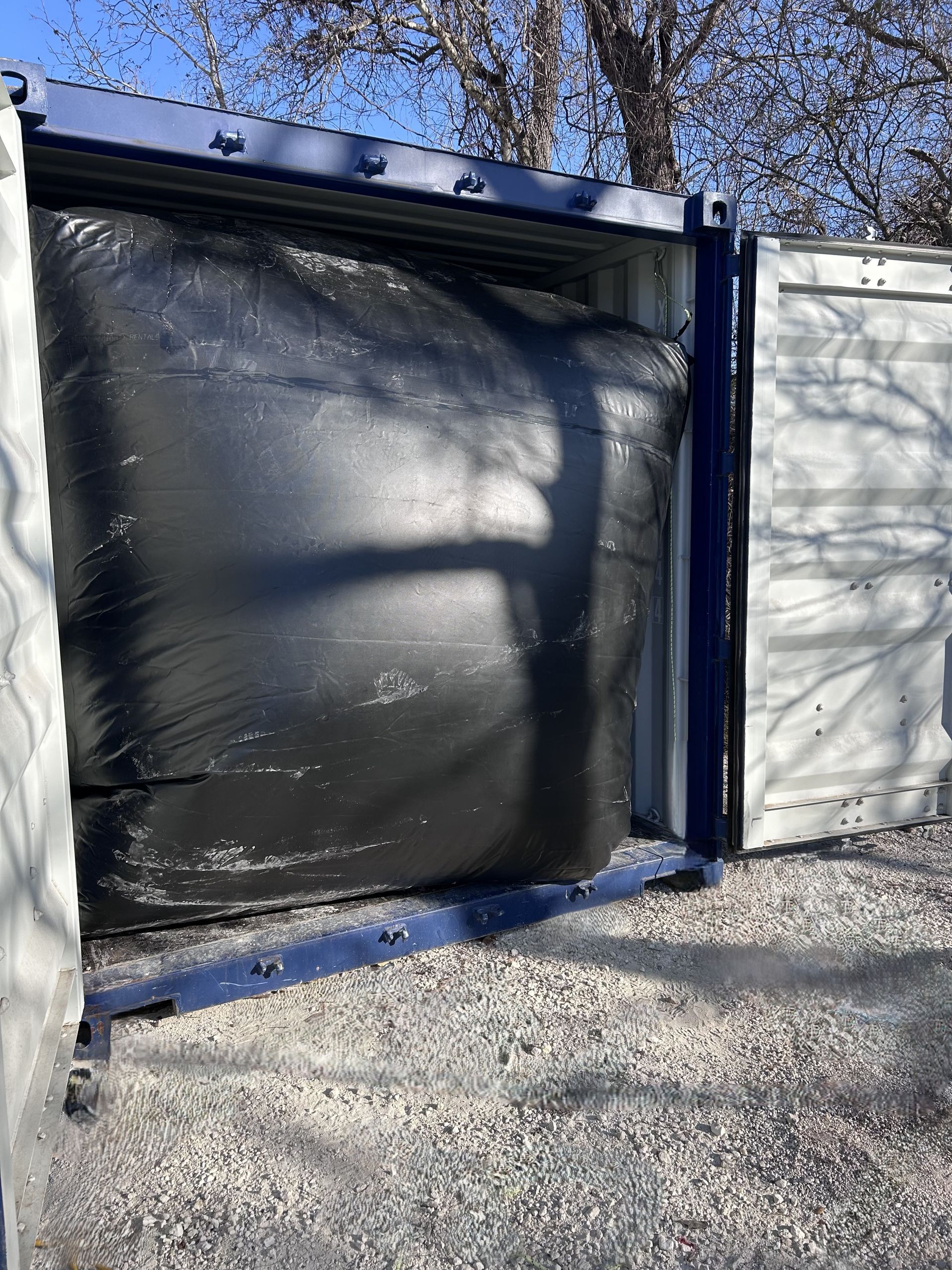 A large black bag is sitting inside of a shipping container.