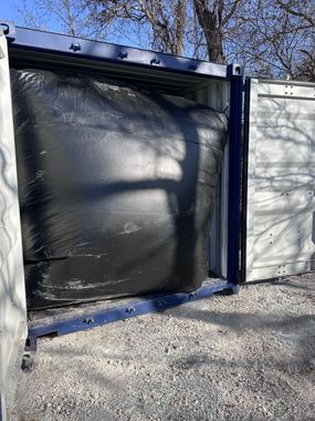 A large black bag is sitting inside of a shipping container.