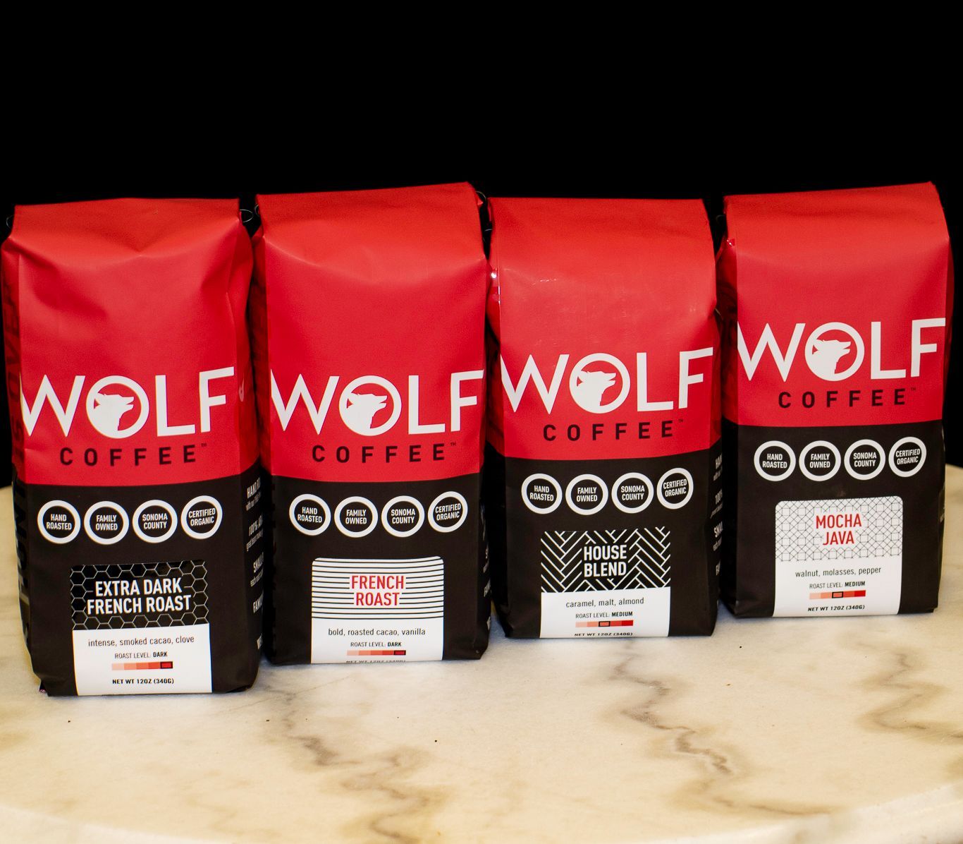 Four red and black Wolf Coffee bags with different coffee varieties.