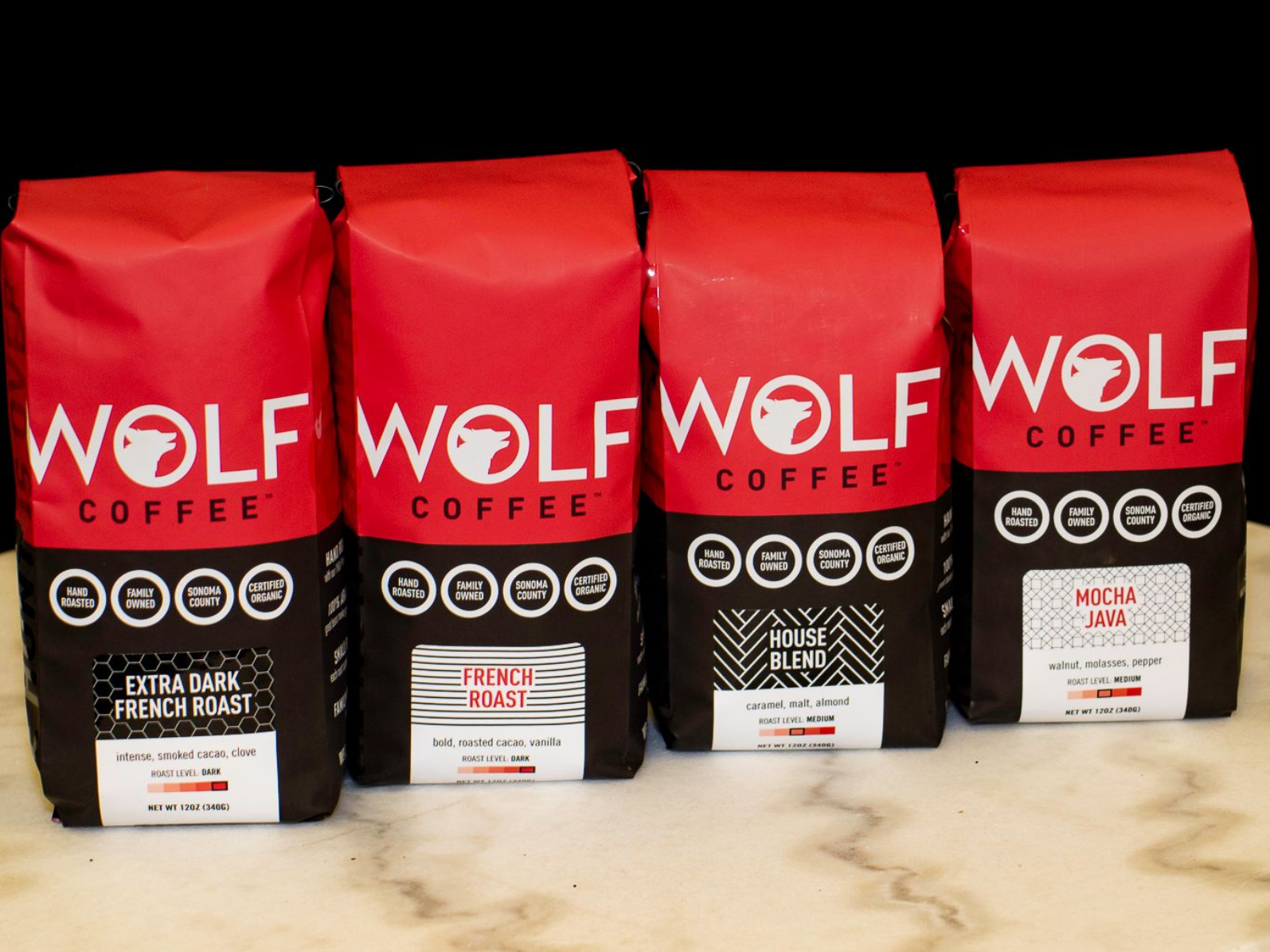 Four red bags of Wolf Coffee, with different blend labels, sit side-by-side.