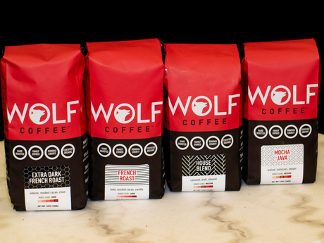 Four red bags of Wolf Coffee, with different blend labels, sit side-by-side.