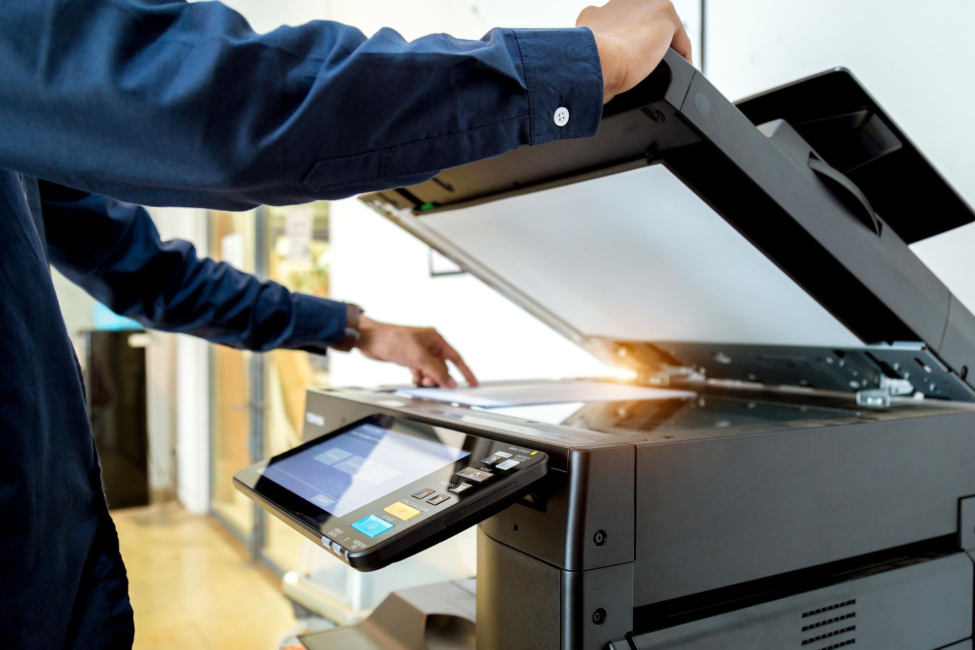Person using a copier, lifting the lid, preparing to scan a document.