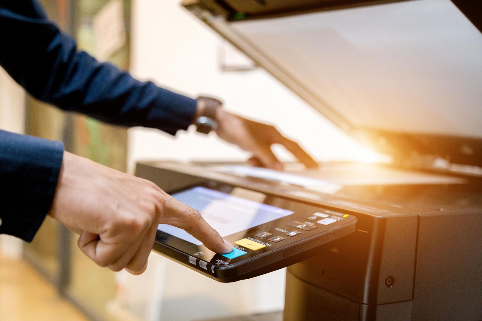 Person in suit uses a photocopier, pressing a button on the control panel.
