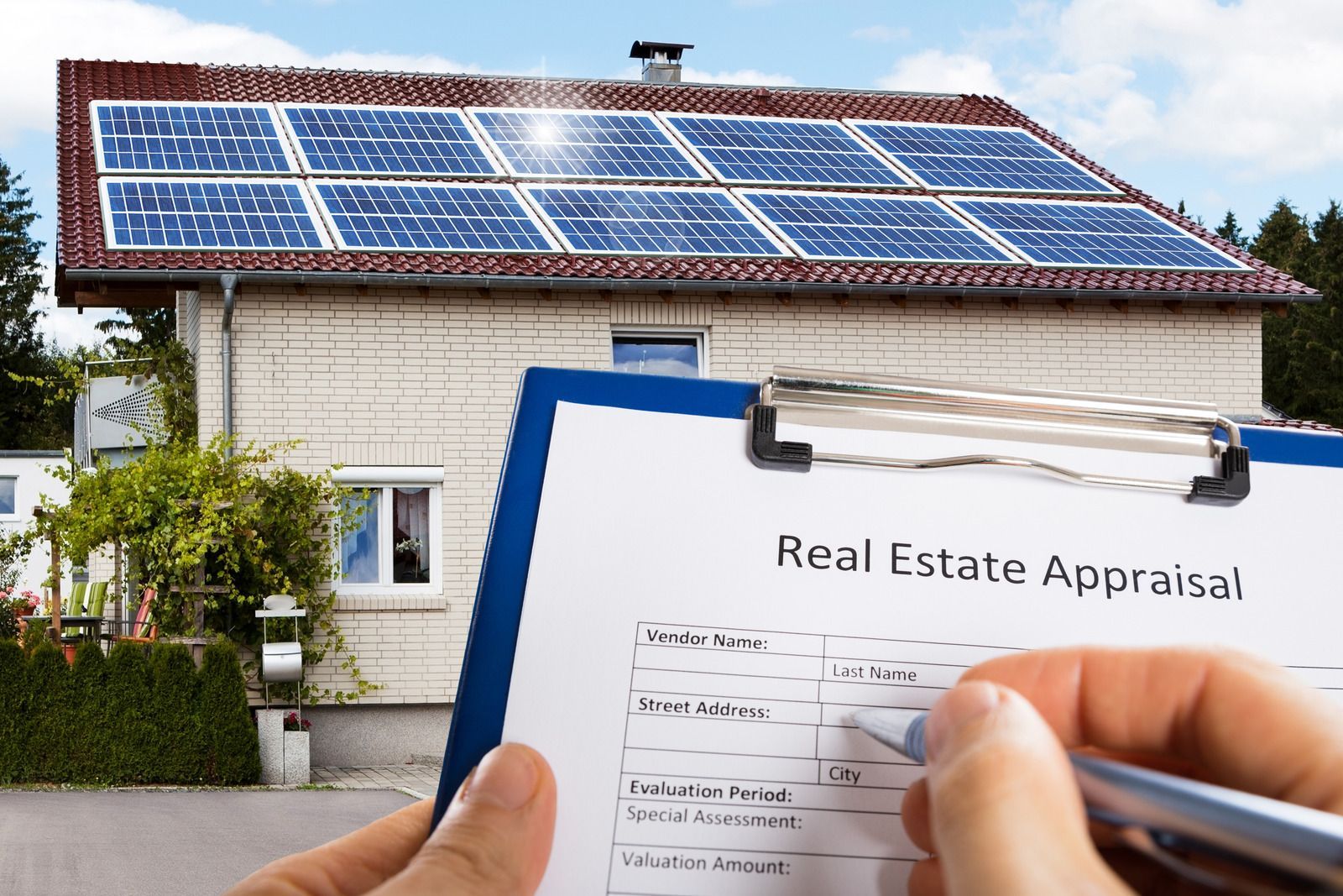A person filling out a real estate appraisal form in front of a house with solar panels.