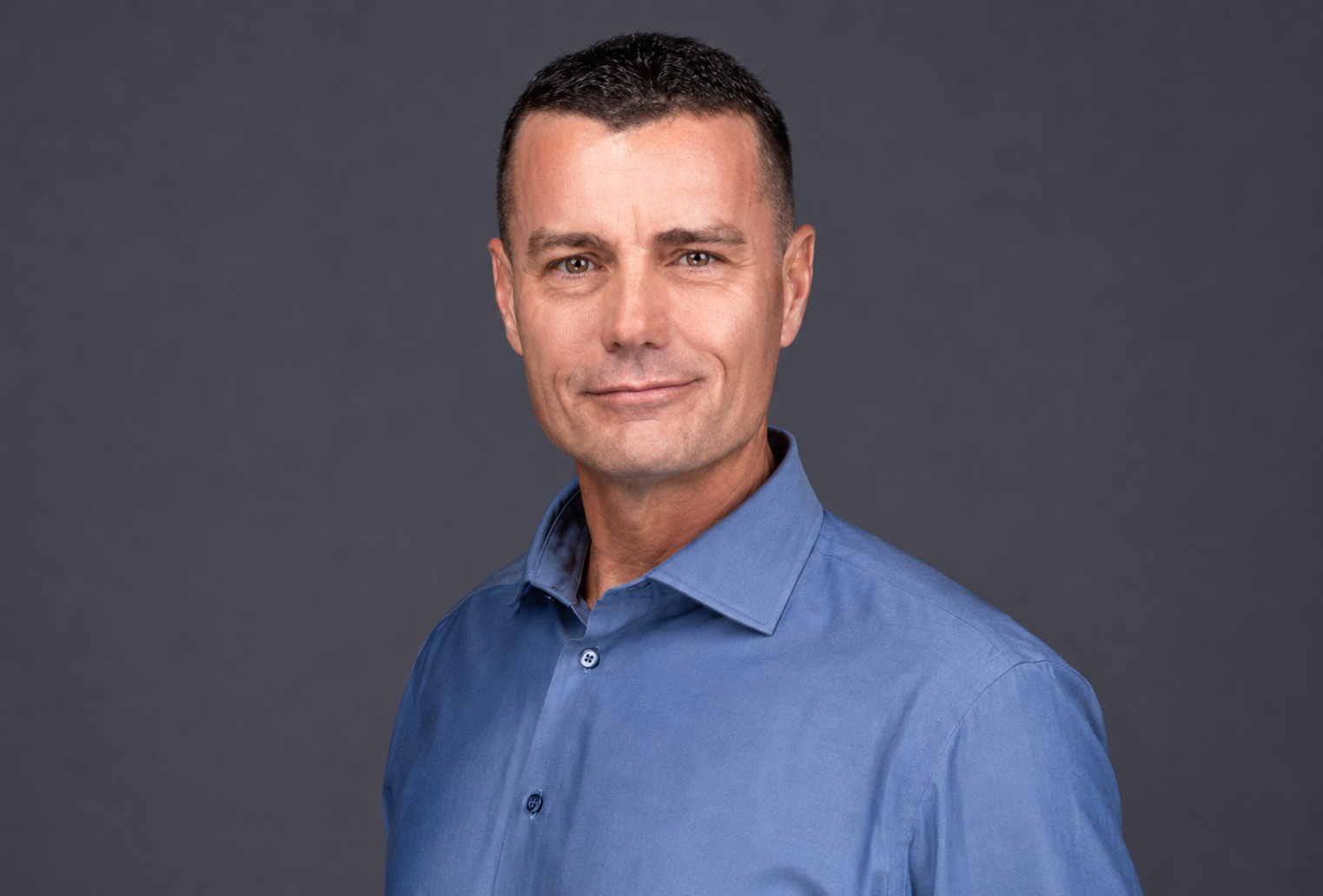 Bill Schauman Personal Injury Lawyer CA Portrait of a man in a blue shirt against a dark gray background